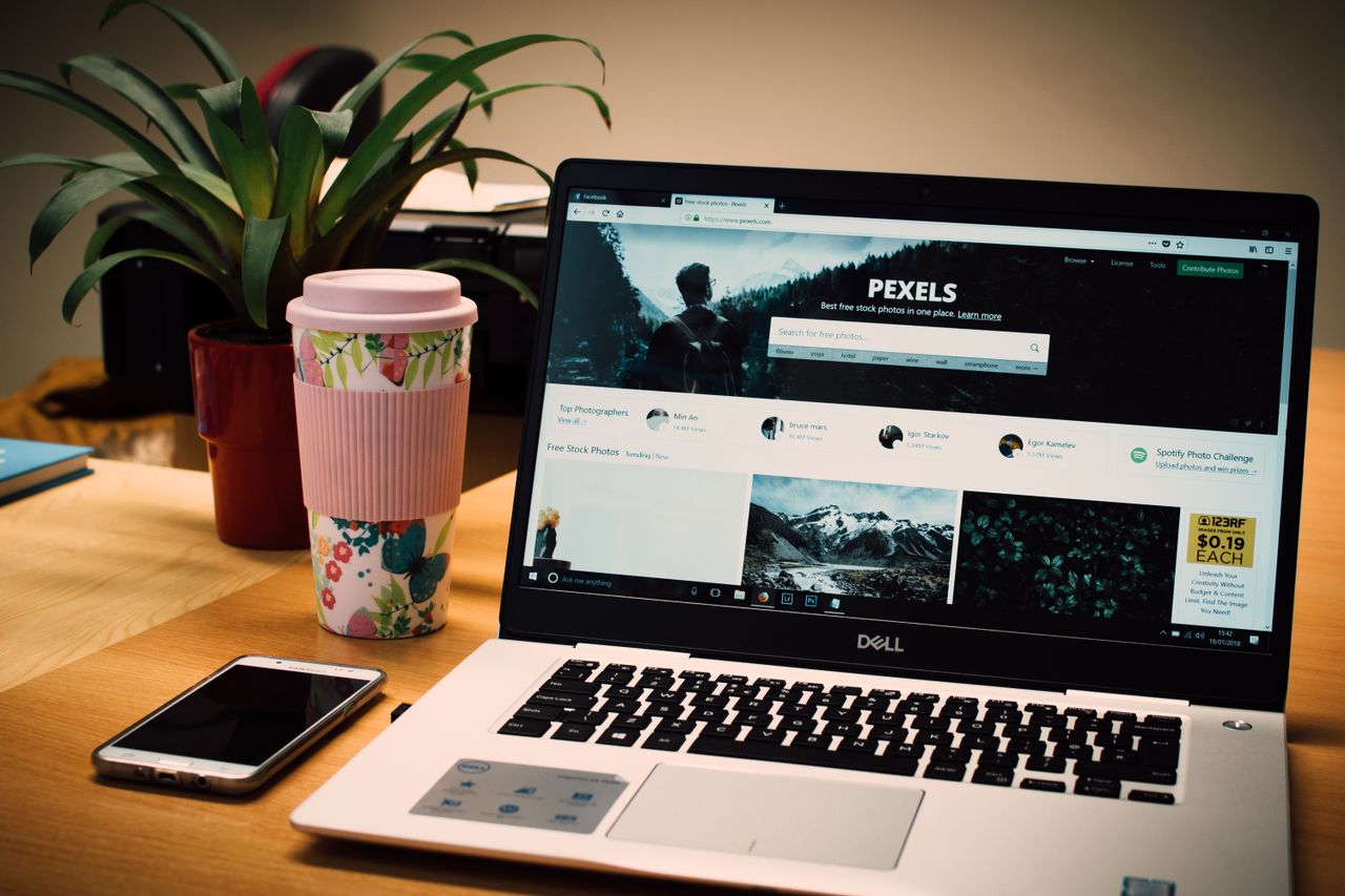 our-story A neat desk setup with a laptop displaying a stock photo website and a smartphone.